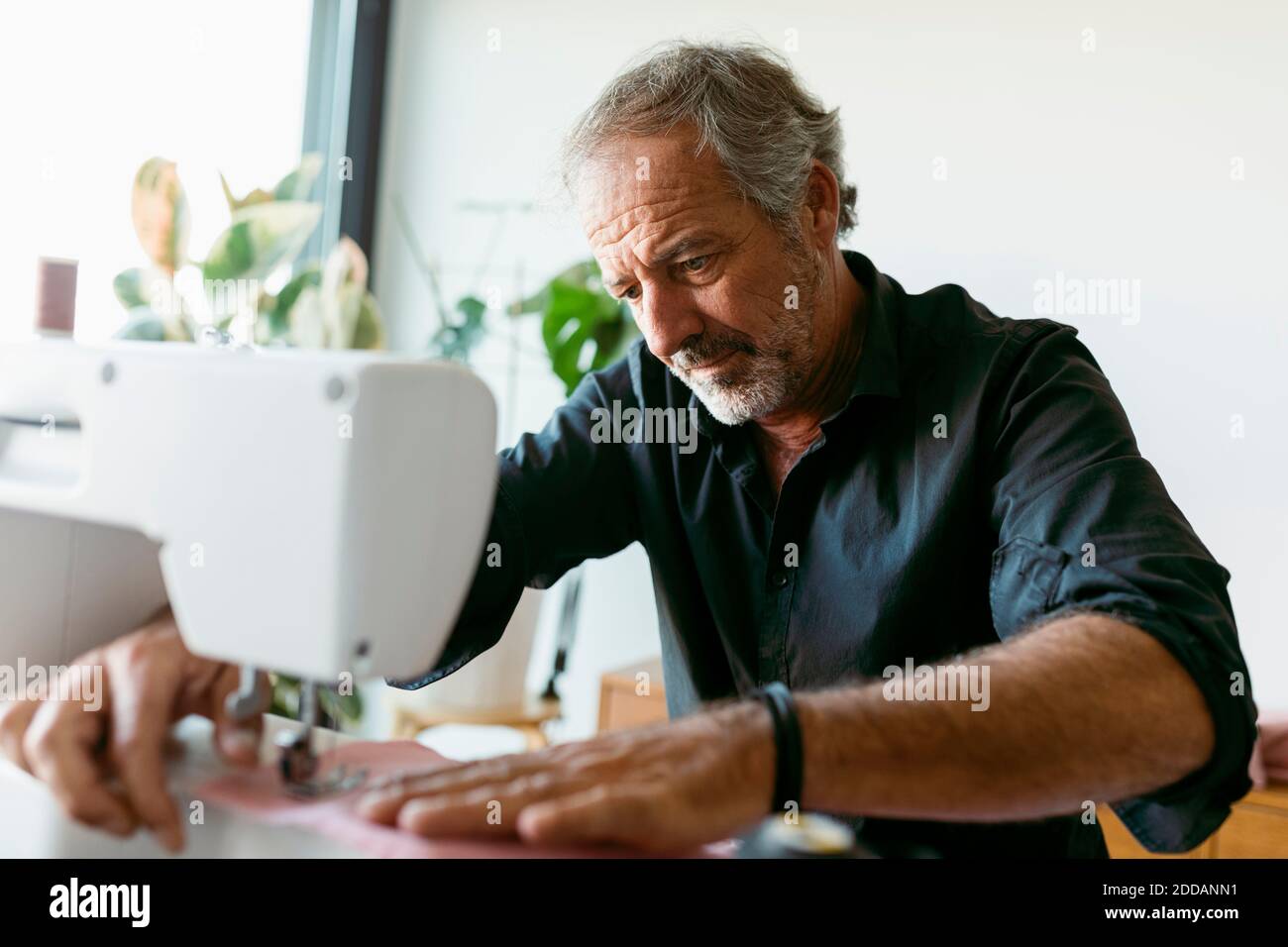 Male costume designer using sewing machine while working in studio ...