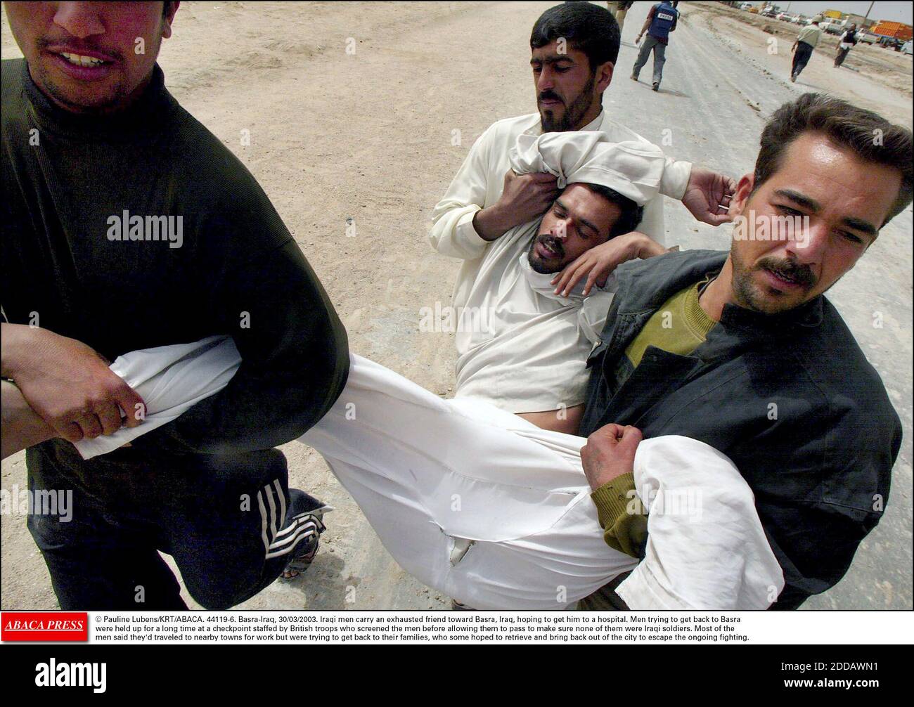NO FILM, NO VIDEO, NO TV, NO DOCUMENTARY - © Pauline Lubens/KRT/ABACA. 44119-6. Basra-Iraq, 30/03/2003. Iraqi men carry an exhausted friend toward Basra, Iraq, hoping to get him to a hospital. Men trying to get back to Basrawere held up for a long time at a checkpoint staffed by British troops who Stock Photo
