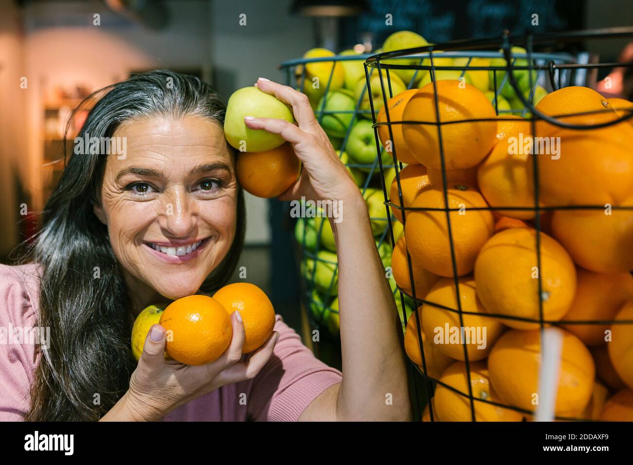 Smiling woman holding fresh fruits in metallic basket at cafe Stock ...