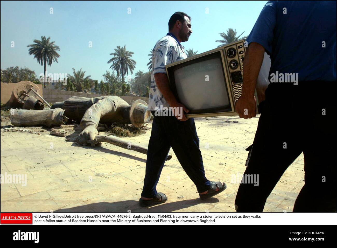 NO FILM, NO VIDEO, NO TV, NO DOCUMENTARY - © David P. Gilkey/Detroit free  press/KRT/ABACA. 44576-6. Baghdad-Iraq, 11/04/03. Iraqi men carry a stolen  television set as they walks past a fallen statue