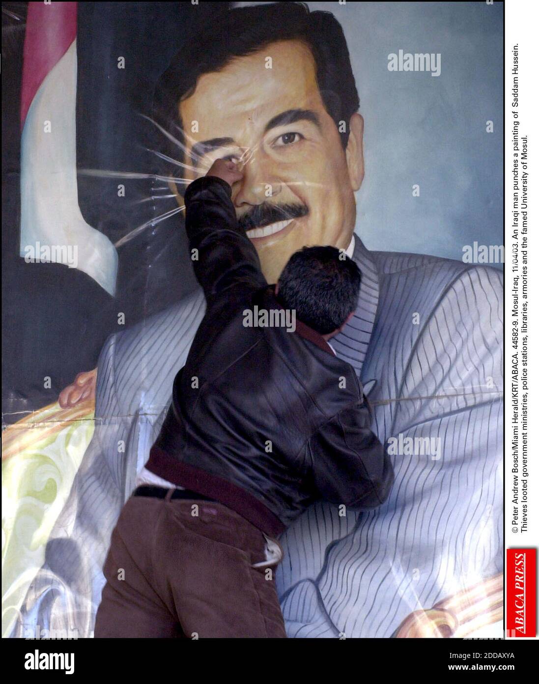 NO FILM, NO VIDEO, NO TV, NO DOCUMENTARY - © Peter Andrew Bosch/Miami Herald/KRT/ABACA. 44582-9. Mosul-Iraq, 11/04/03. An Iraqi man punches a painting of Saddam Hussein. Thieves looted government ministries, police stations, libraries, armories and the famed University of Mosul. Stock Photo