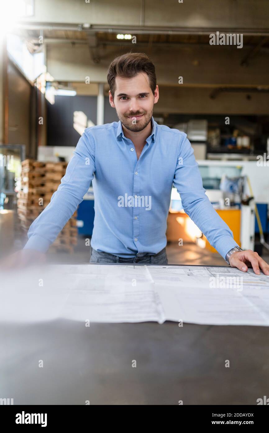 Smiling man leaning on table while working  at factory Stock Photo
