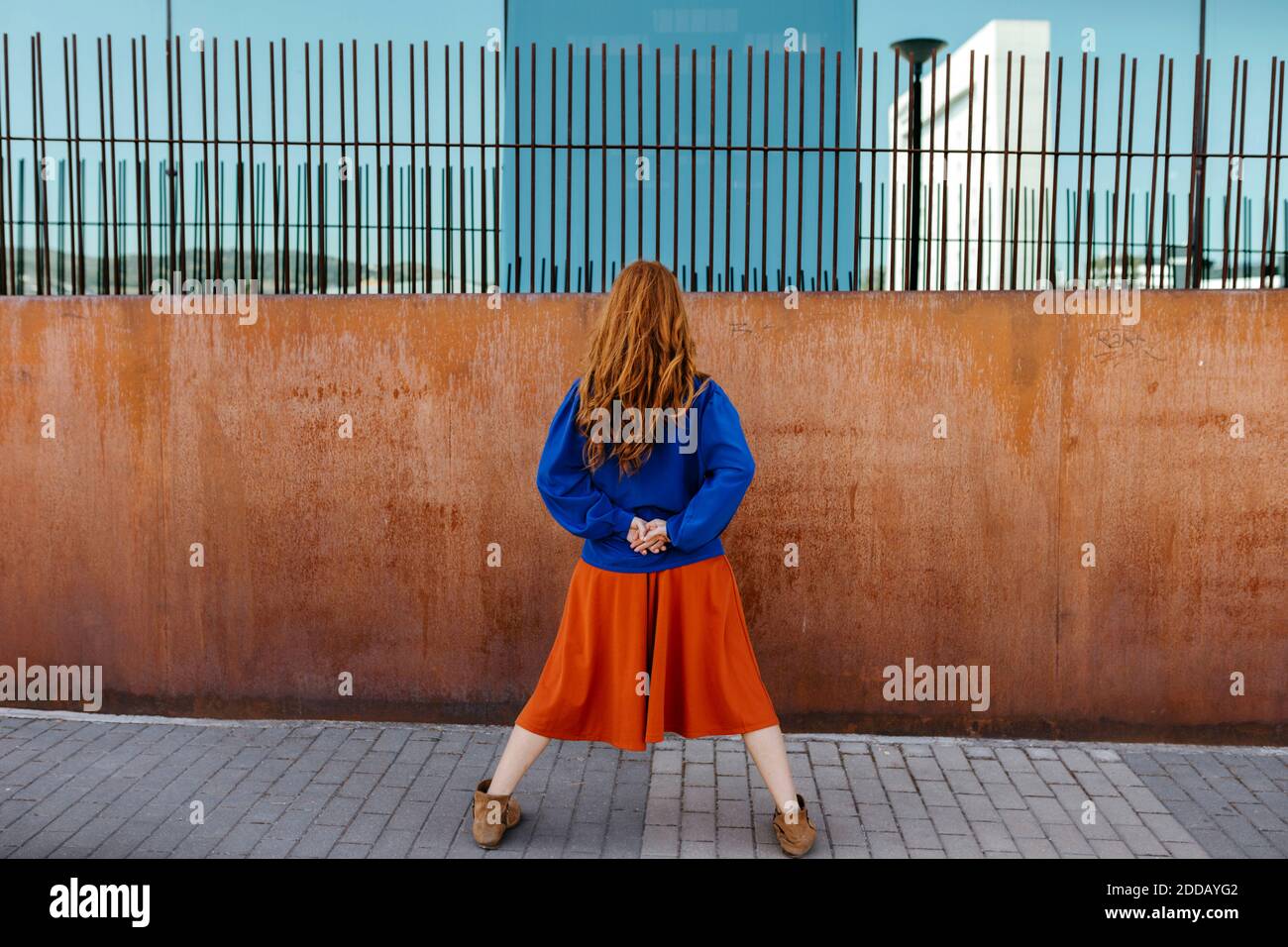 Rear view of woman standing with legs apart while facing wall Stock ...