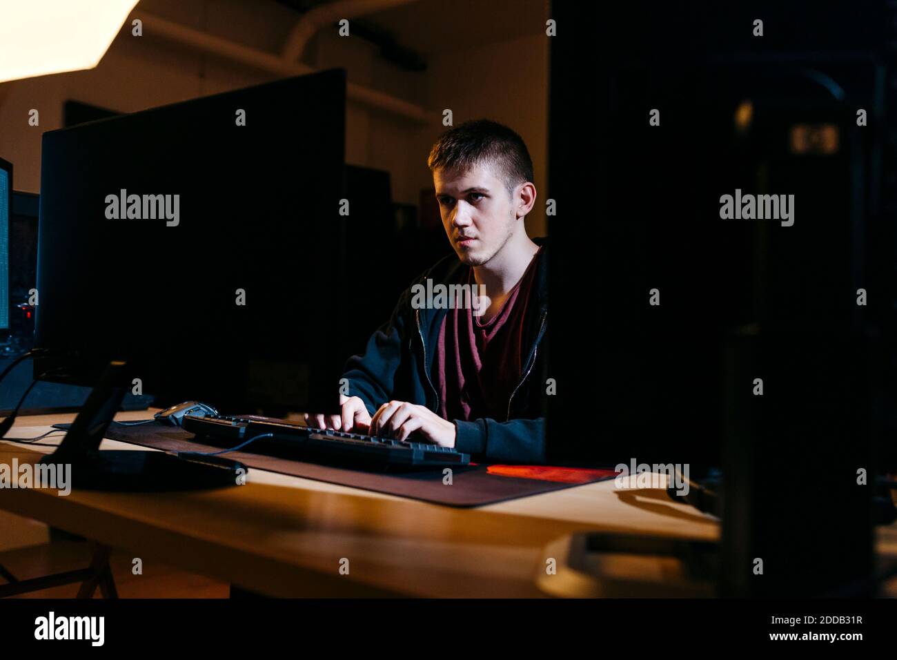 Young computer hacker working while sitting at office Stock Photo