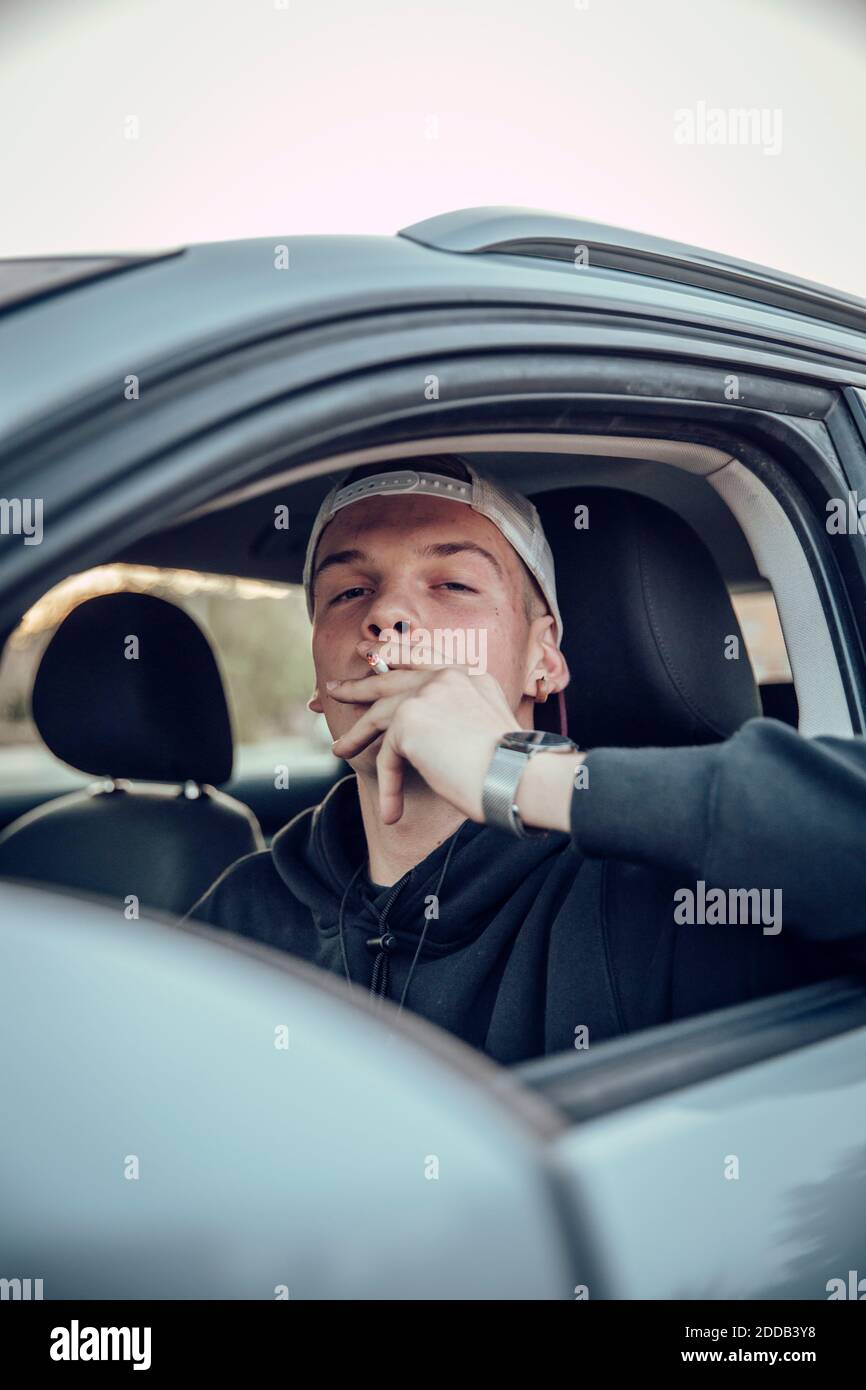 Young man smoking cigarette in car Stock Photo