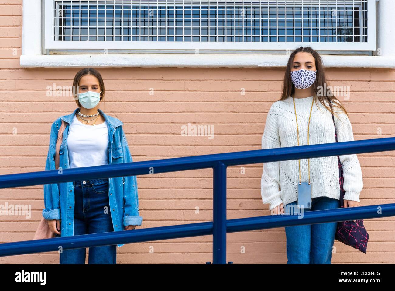 Female friends wearing protective face mask social distancing against