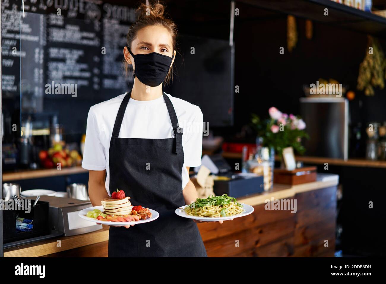 Portrait of barista wearing protective mask while serving food in ...