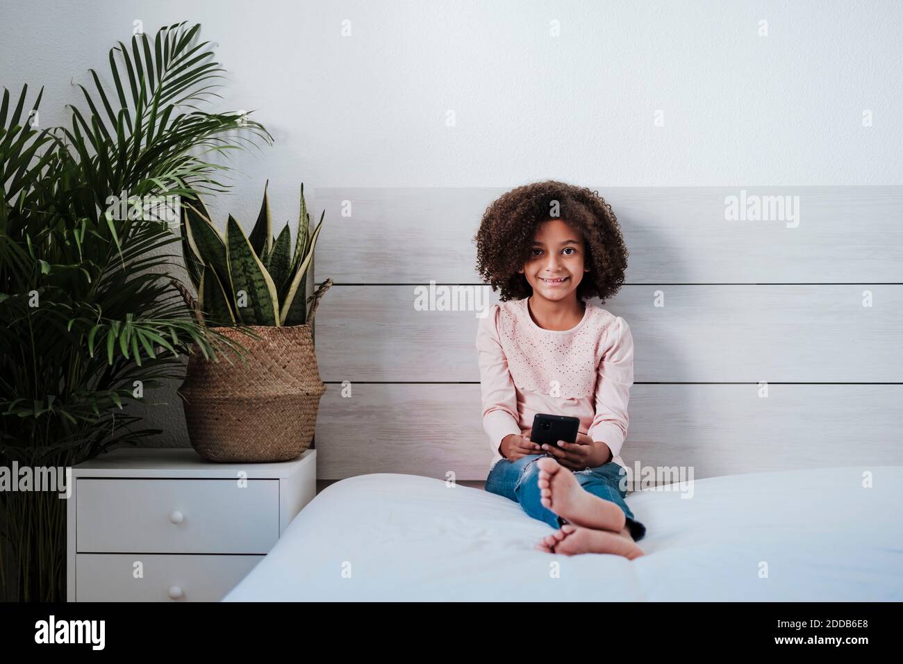 Cute girl using smart phone sitting in bedroom at home Stock Photo - Alamy