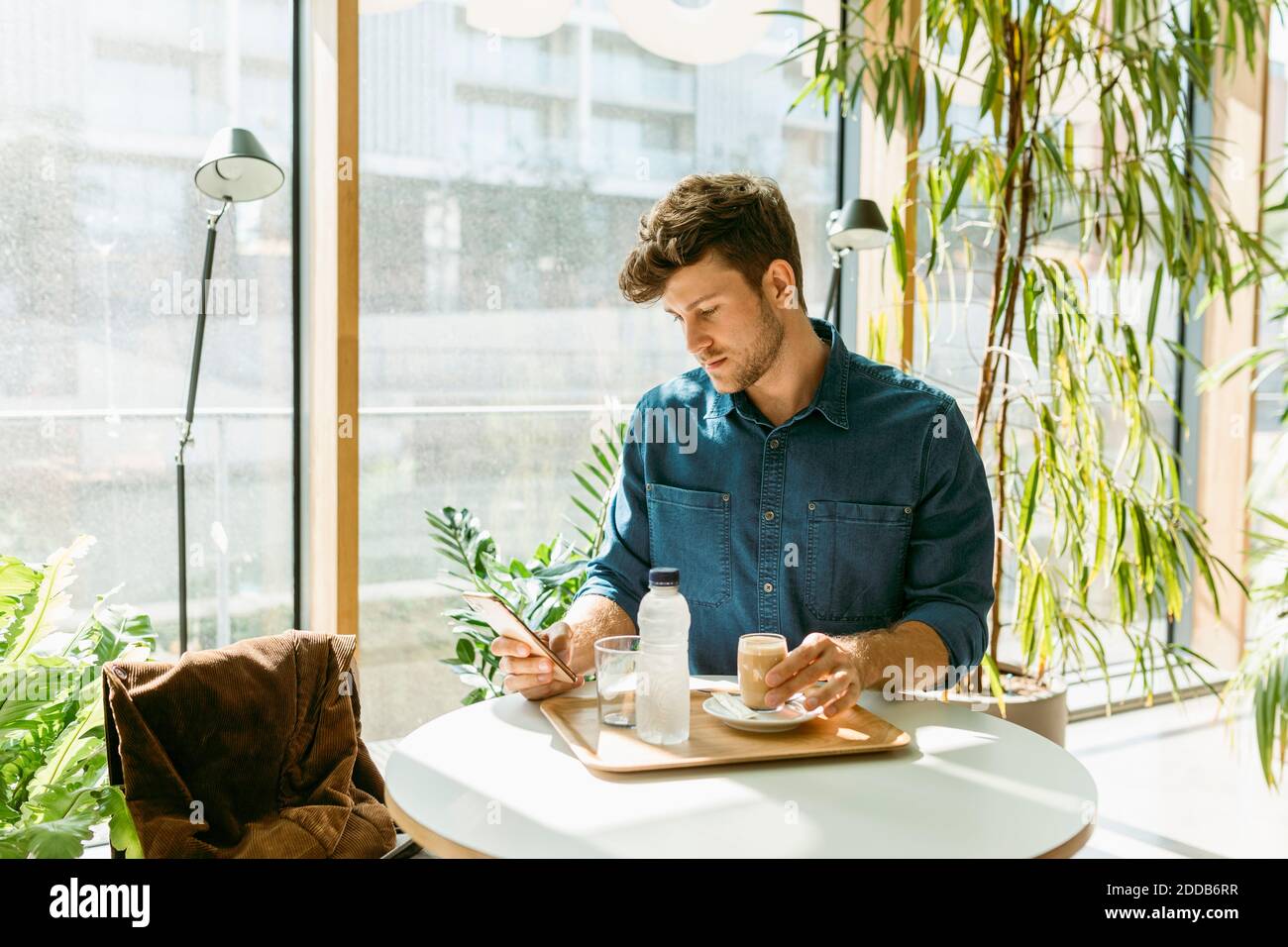 Handsome businessman using smart phone at table in cafe Stock Photo