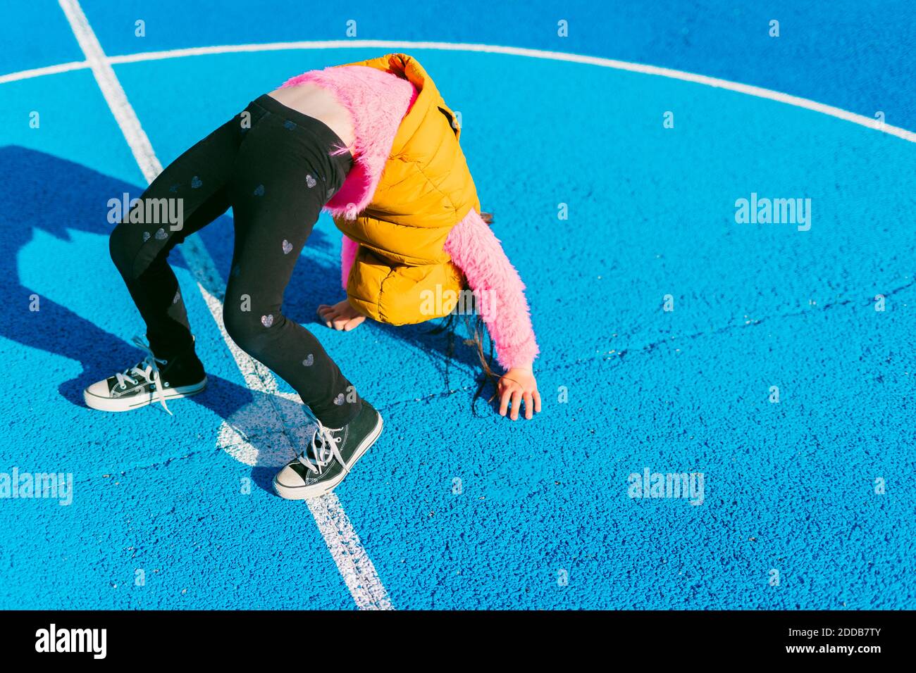 Girl doing acrobatic activity on soccer court during sunny day Stock Photo