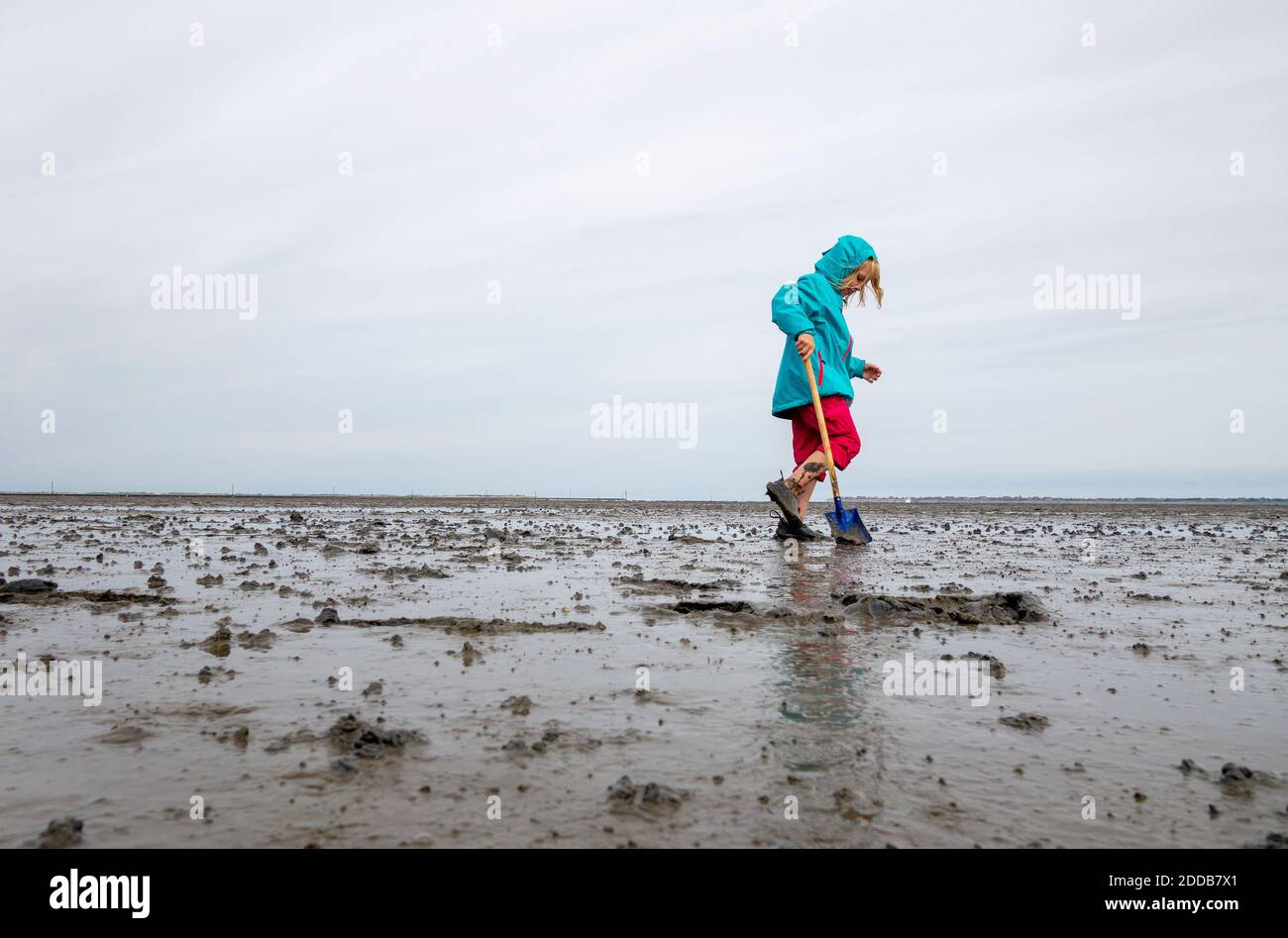 Girl playing in mud flat against sky at Lower Saxon Wadden Sea National Park, Germany Stock Photo