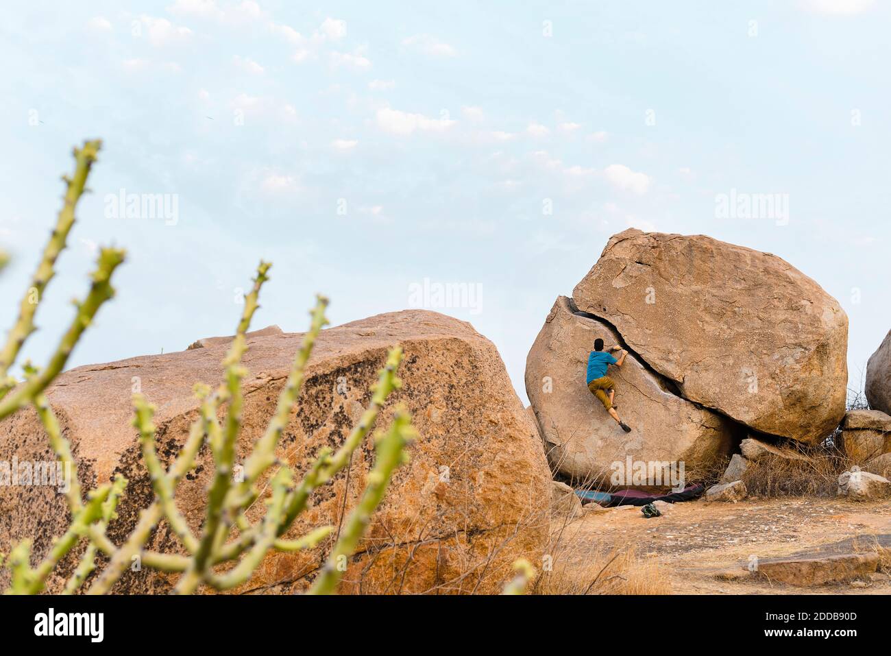 Determinant young man boulderer climbing rock, Karnataka, Hampi, India Stock Photo
