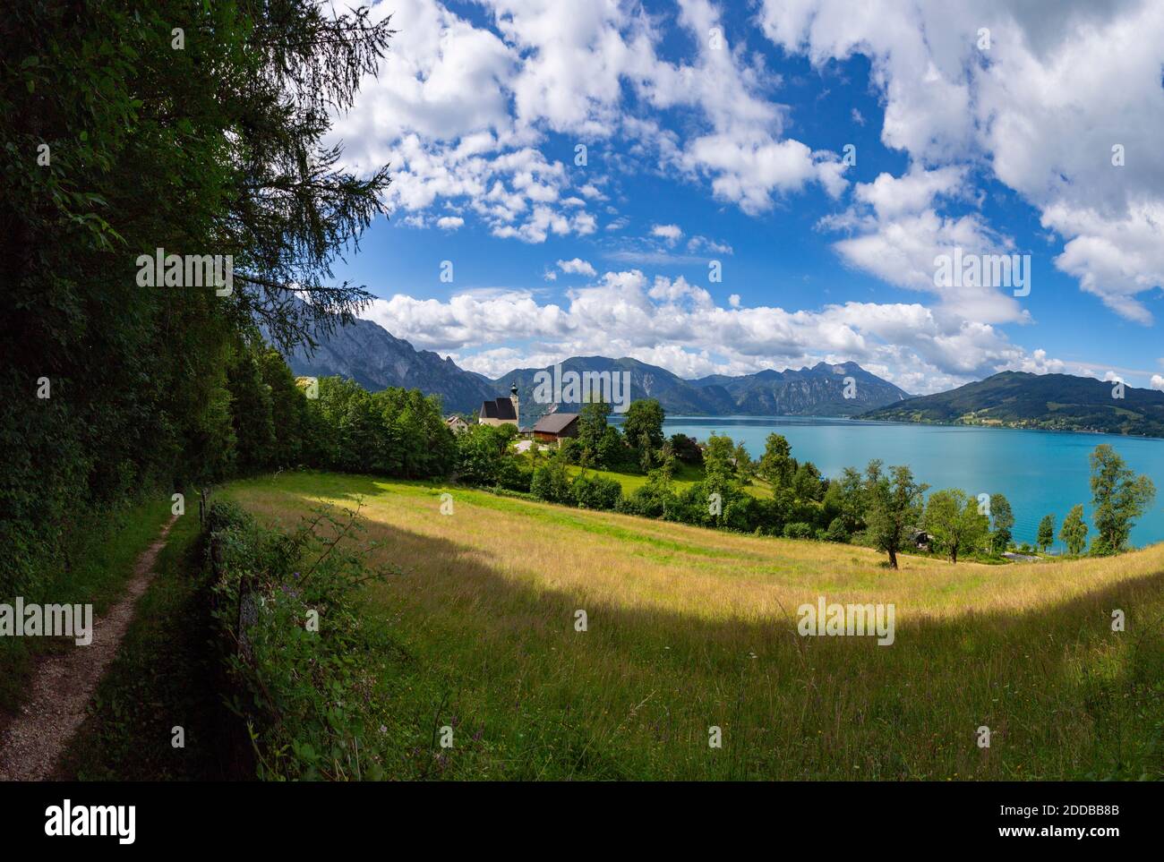 Austria, Upper Austria, Steinbach am Attersee, Footpath stretching along edge of countryside meadow in summer with Lake Atter in background Stock Photo