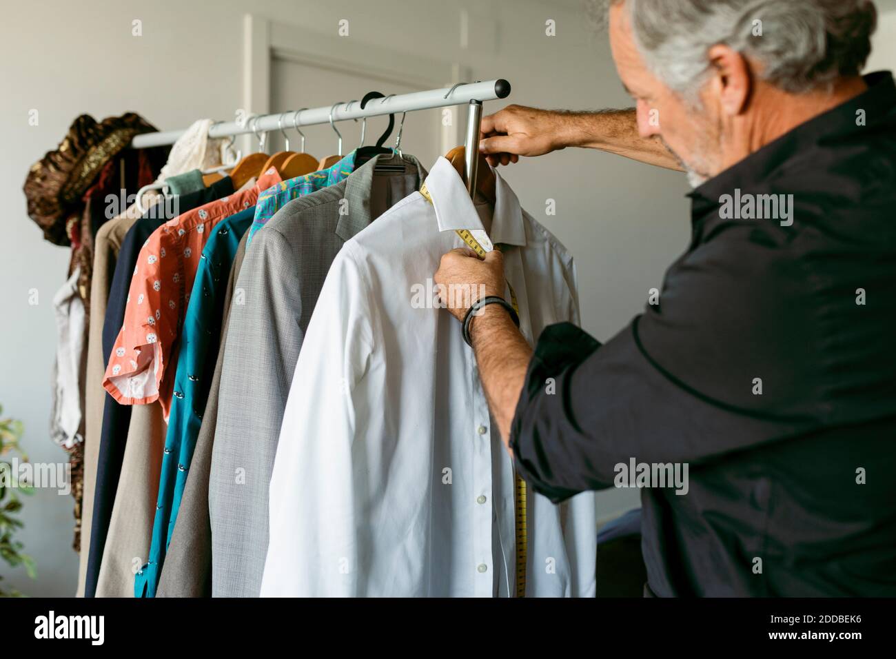 Tailor measuring shirt with tape measure at workplace Stock Photo