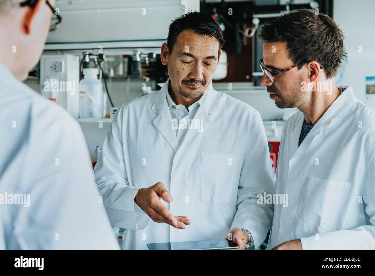 Male scientists using digital tablet while standing at laboratory Stock Photo