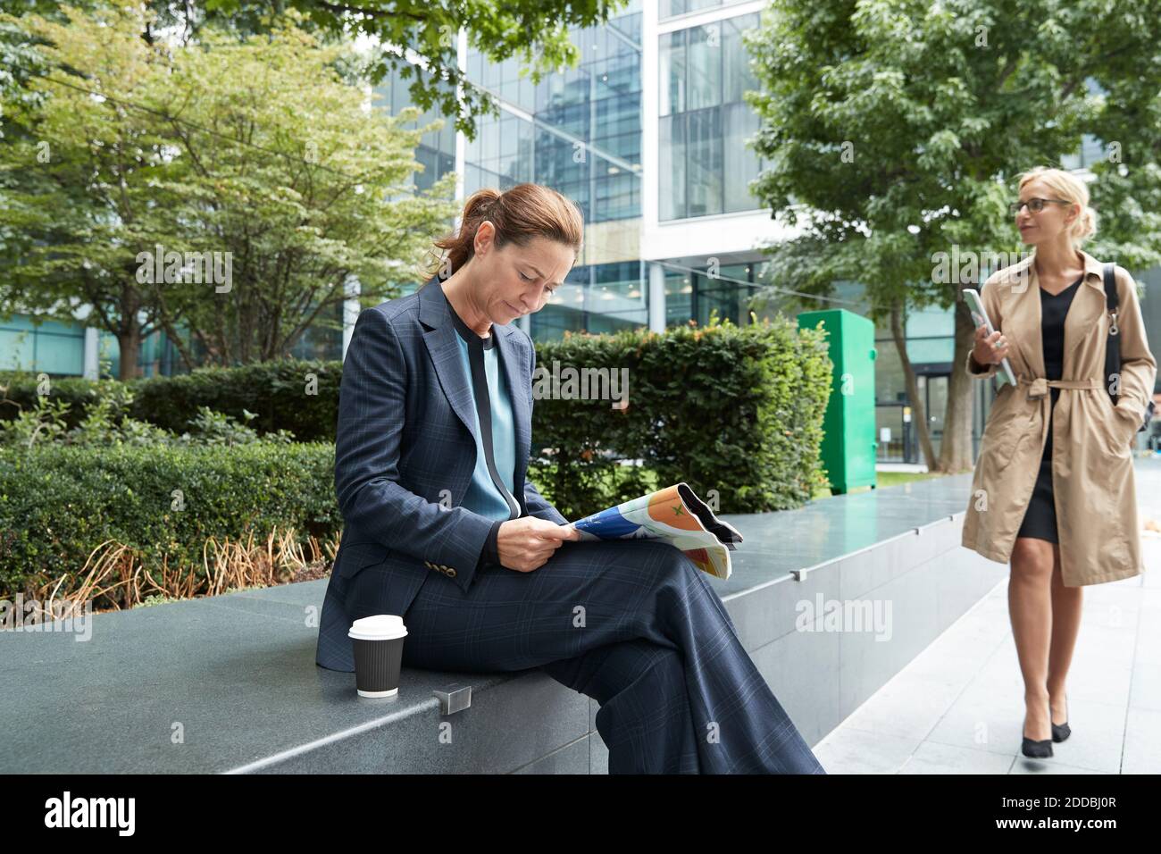 Businesswoman reading paper with colleague leaving after work at city Stock Photo