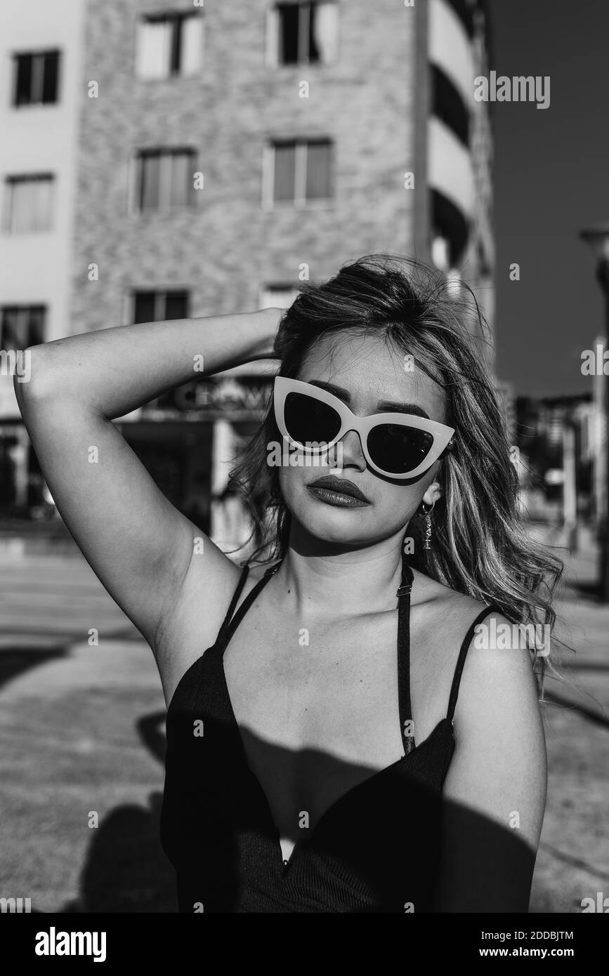 Beautiful young woman with hand in hair standing on street Stock Photo