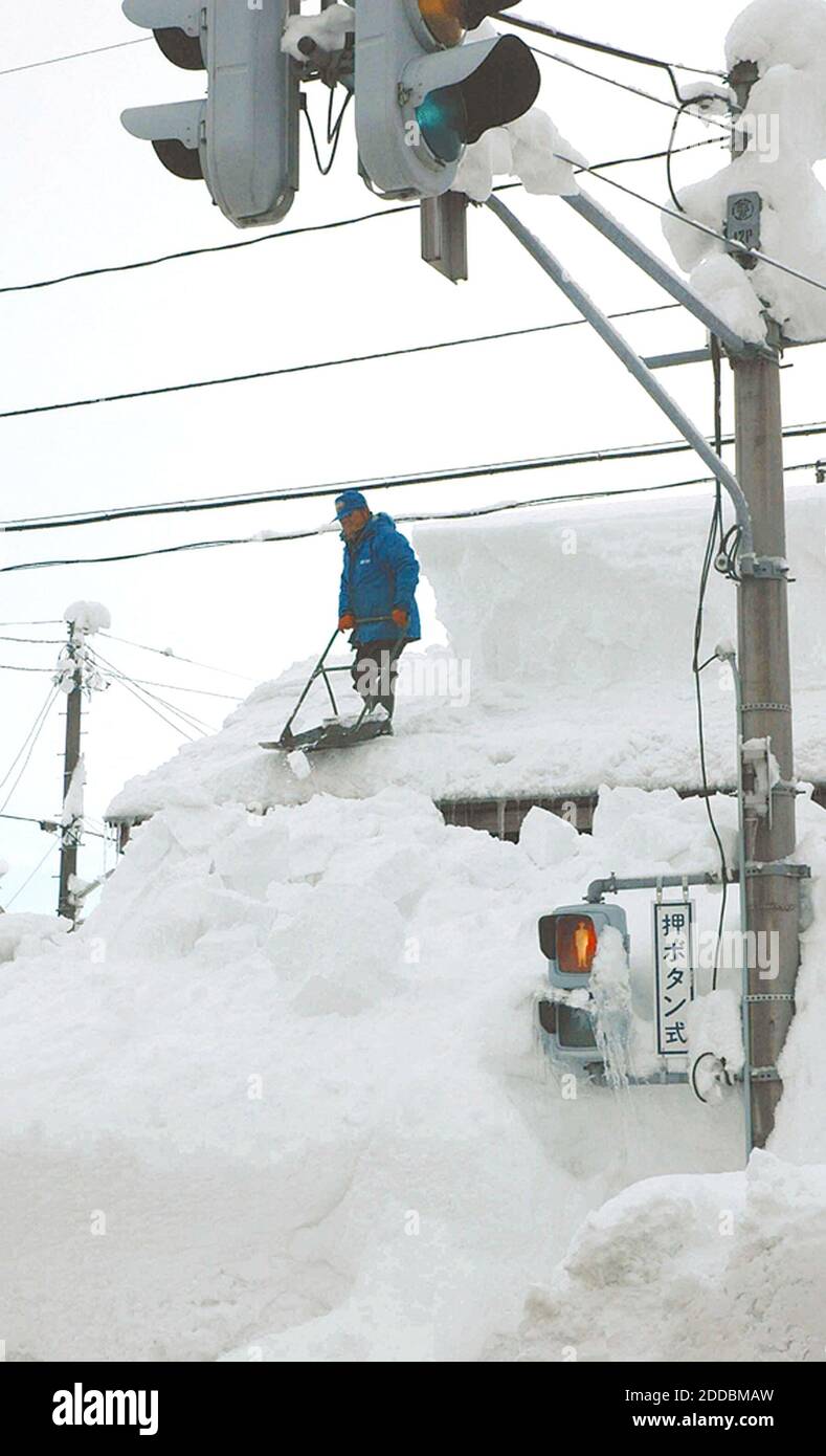NO FILM, NO VIDEO, NO TV, NO DOCUMENTARY - A man shovels snow off a roof in Tsunanmachi, Niigata Prefecture, Japan on Saturday morning, January 7, 2006. 71 people have died due to the snowstorms which have brought record-breaking amounts for the month of January. Photo by Yomiuri Shimbun/KRT/ABACAPRESS.COM Stock Photo