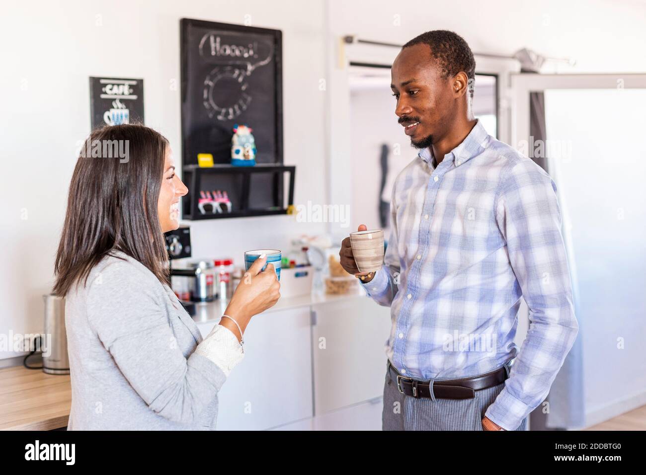 Smiling male and female entrepreneurs talking while having coffee during break in office Stock Photo