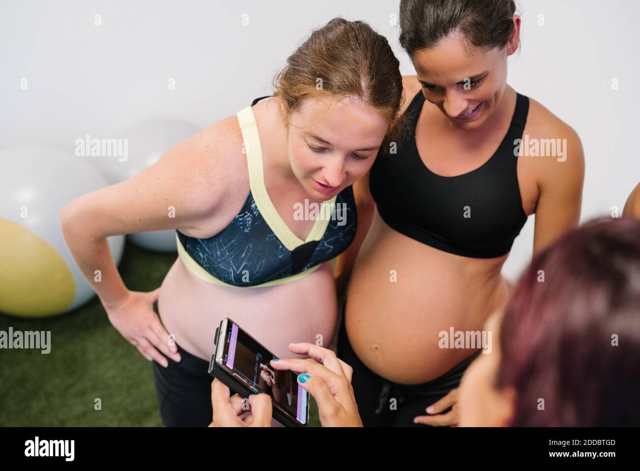 Pregnant woman in sports bra using smart phone in doorway at home Stock  Photo - Alamy