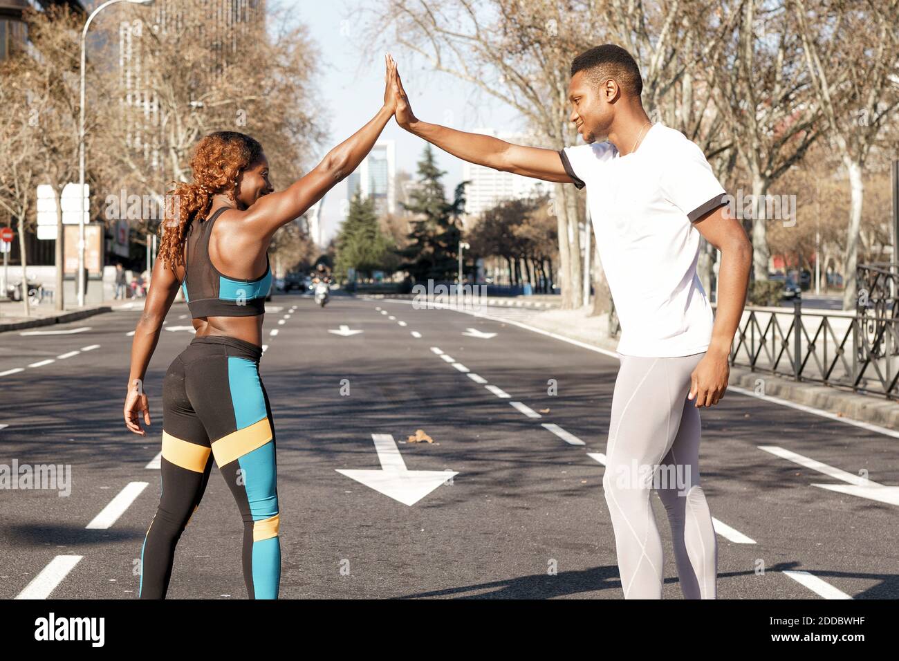 Athletes giving high five before race while standing on road at city Stock Photo
