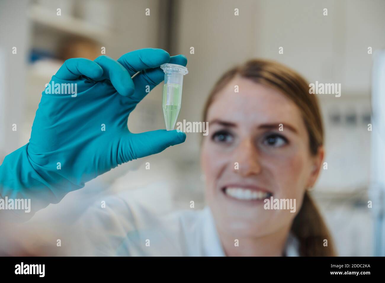 Smiling woman looking at testube while holding in hands at laboratory Stock Photo