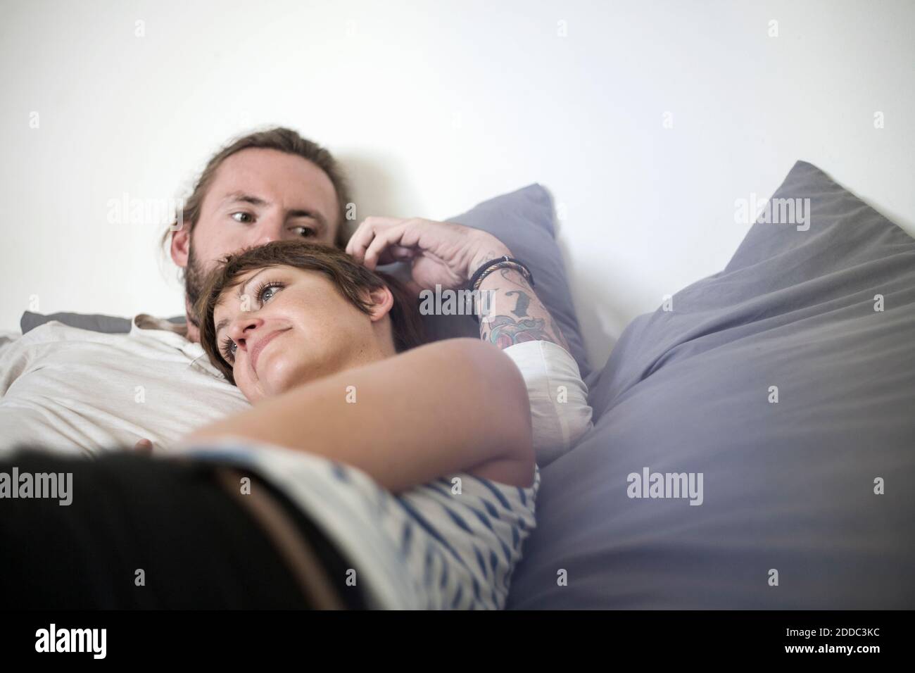 Mid adult man and young woman relaxing on bed in bedroom at home Stock ...