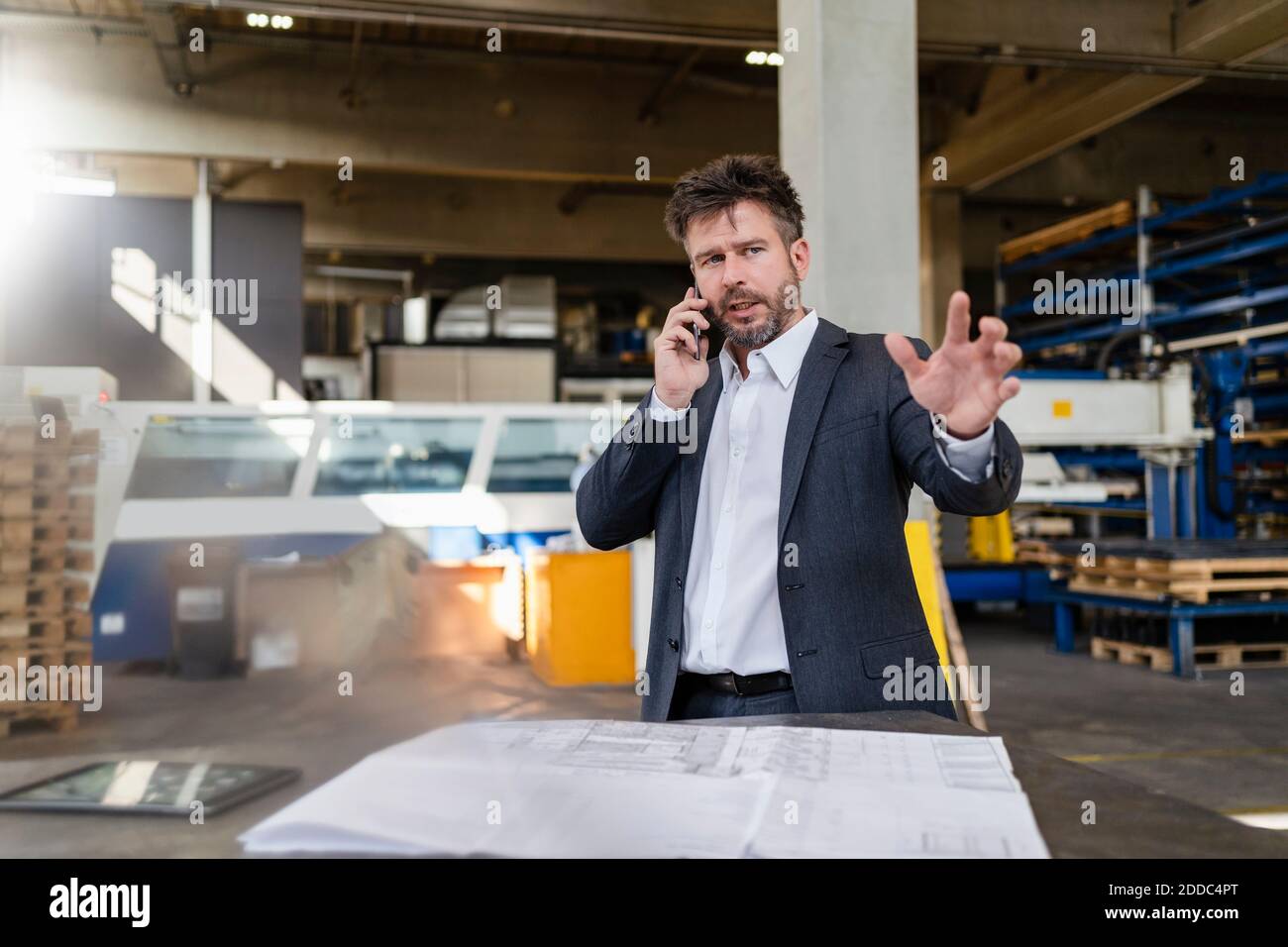 Mature businessman discussing on mobile phone while working at factory Stock Photo