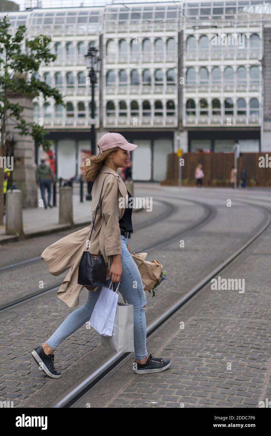 Young woman walking with shopping bags crossing railroad track Stock Photo