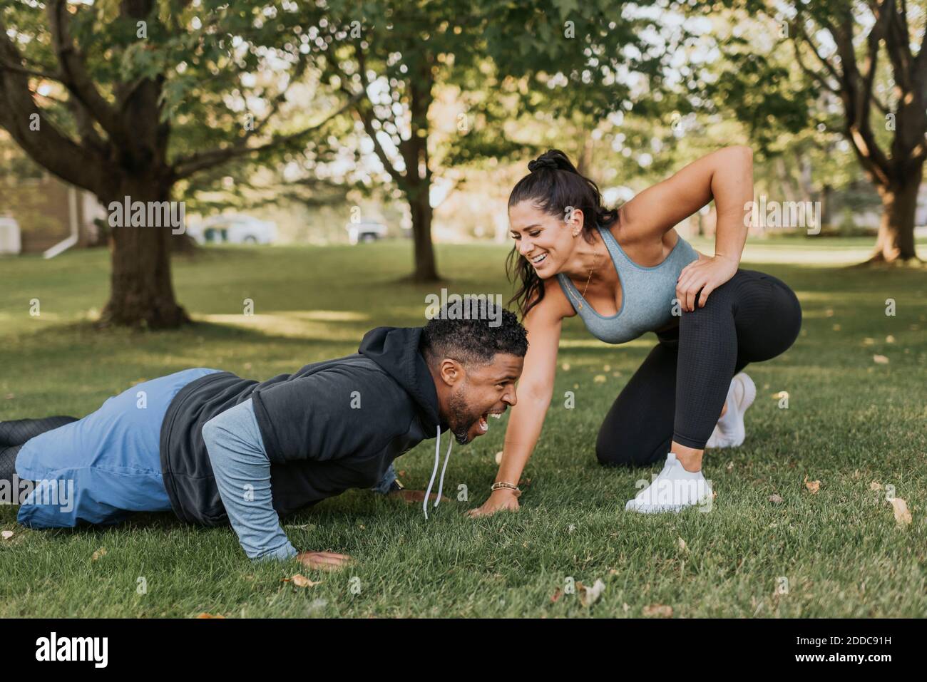 Smiling woman looking at man doing push up at backyard Stock Photo