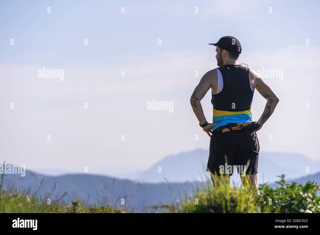 Mid adult man with hand on hip admiring view while standing on mountain Stock Photo