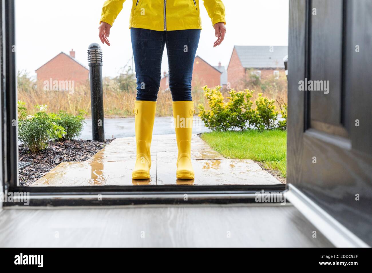 Legs of woman wearing rubber boot standing in back yard Stock Photo