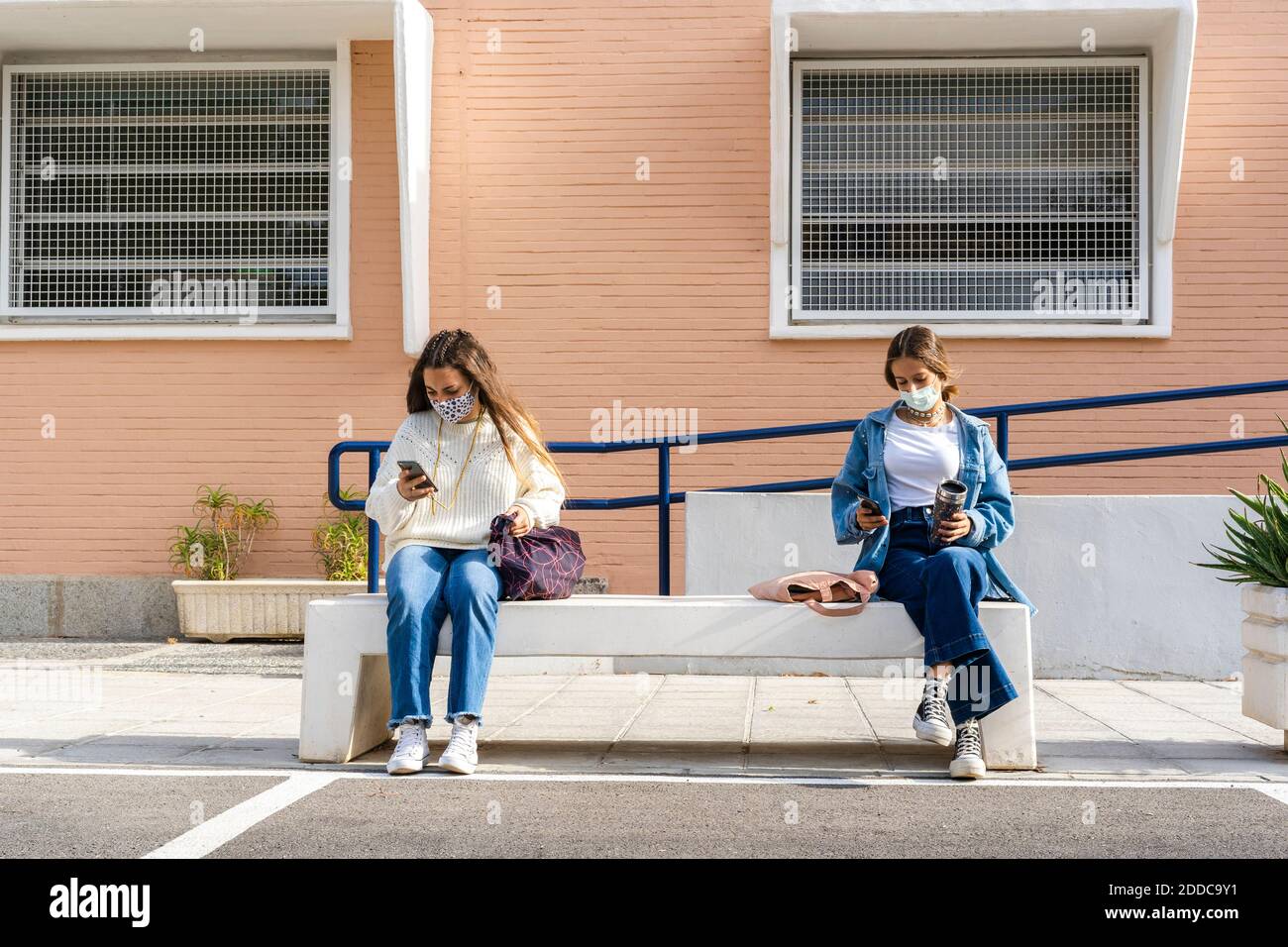Female teenage friends social distancing while using smart phone