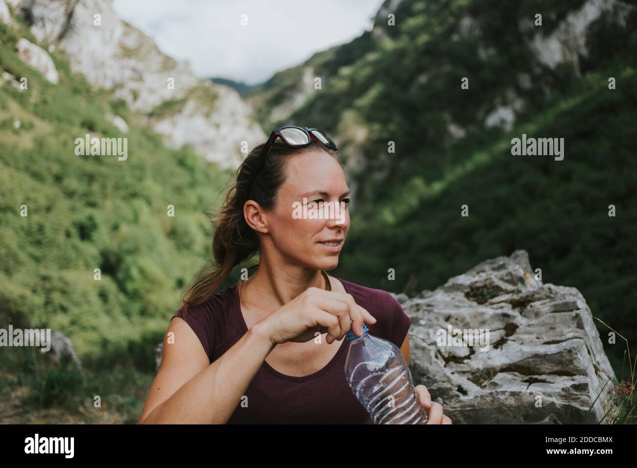 Mid adult female trekker holding water bottle while looking away Stock Photo
