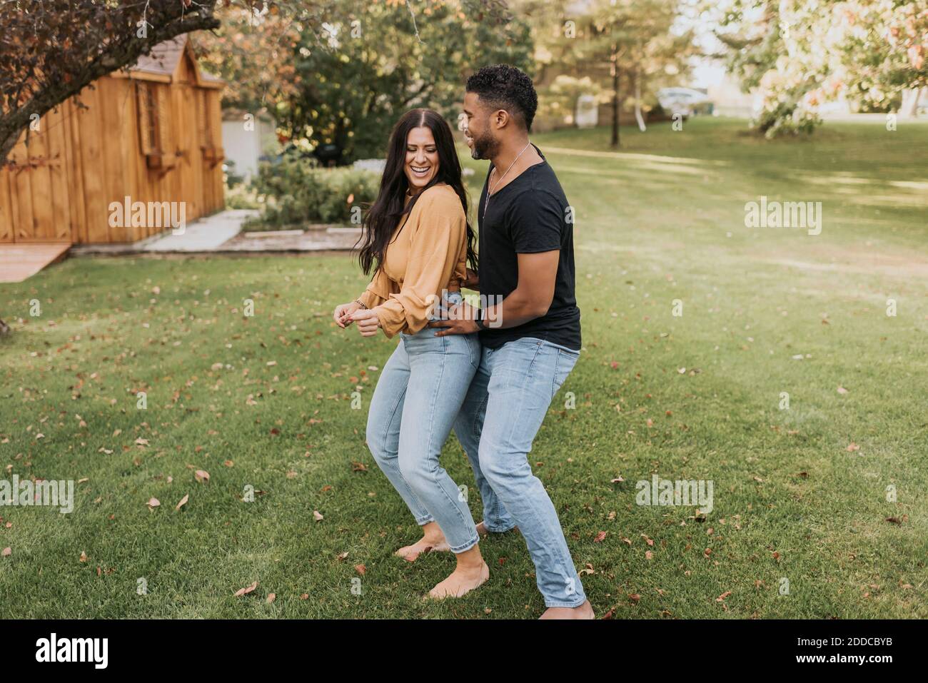 Man with hand on woman hip dancing while standing at backyard Stock Photo