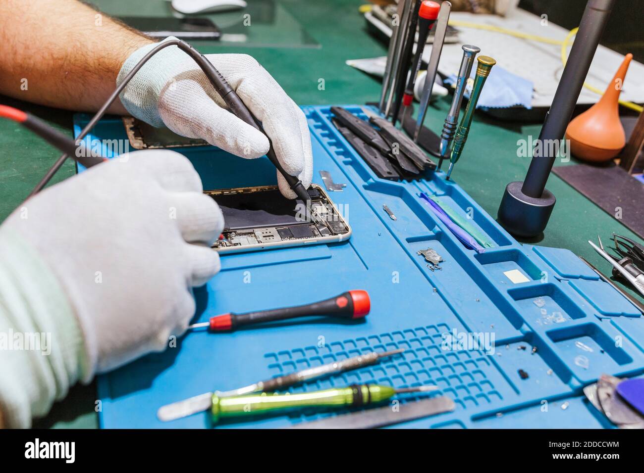Technician examining damaged mobile phone at workbench at repair shop Stock Photo
