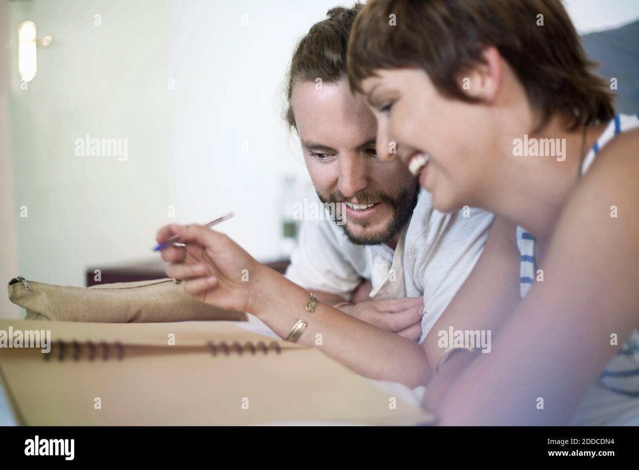 Heterosexual couple writing in book at home Stock Photo