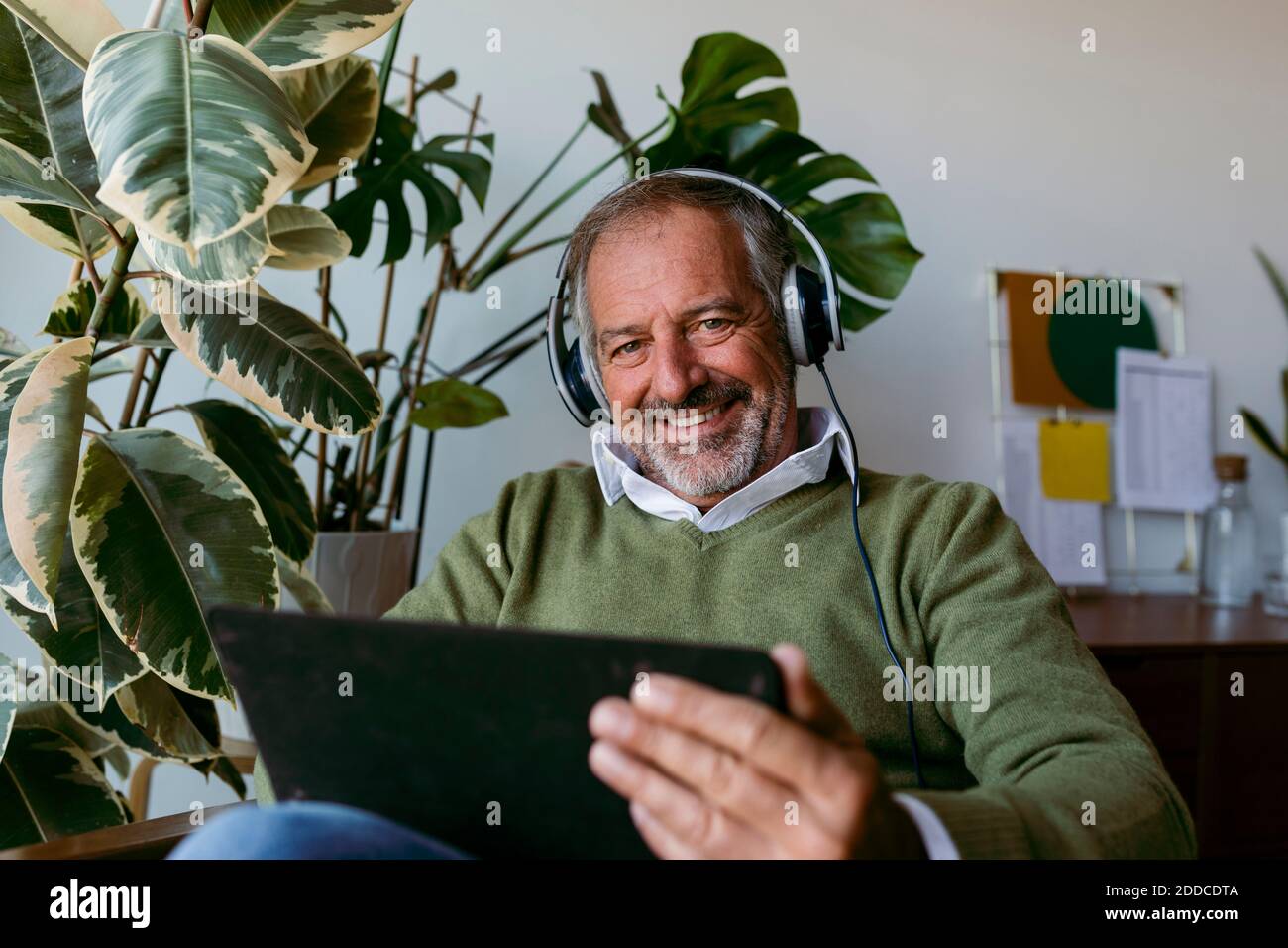 Mature men wearing headphones while using digital tablet at home Stock Photo