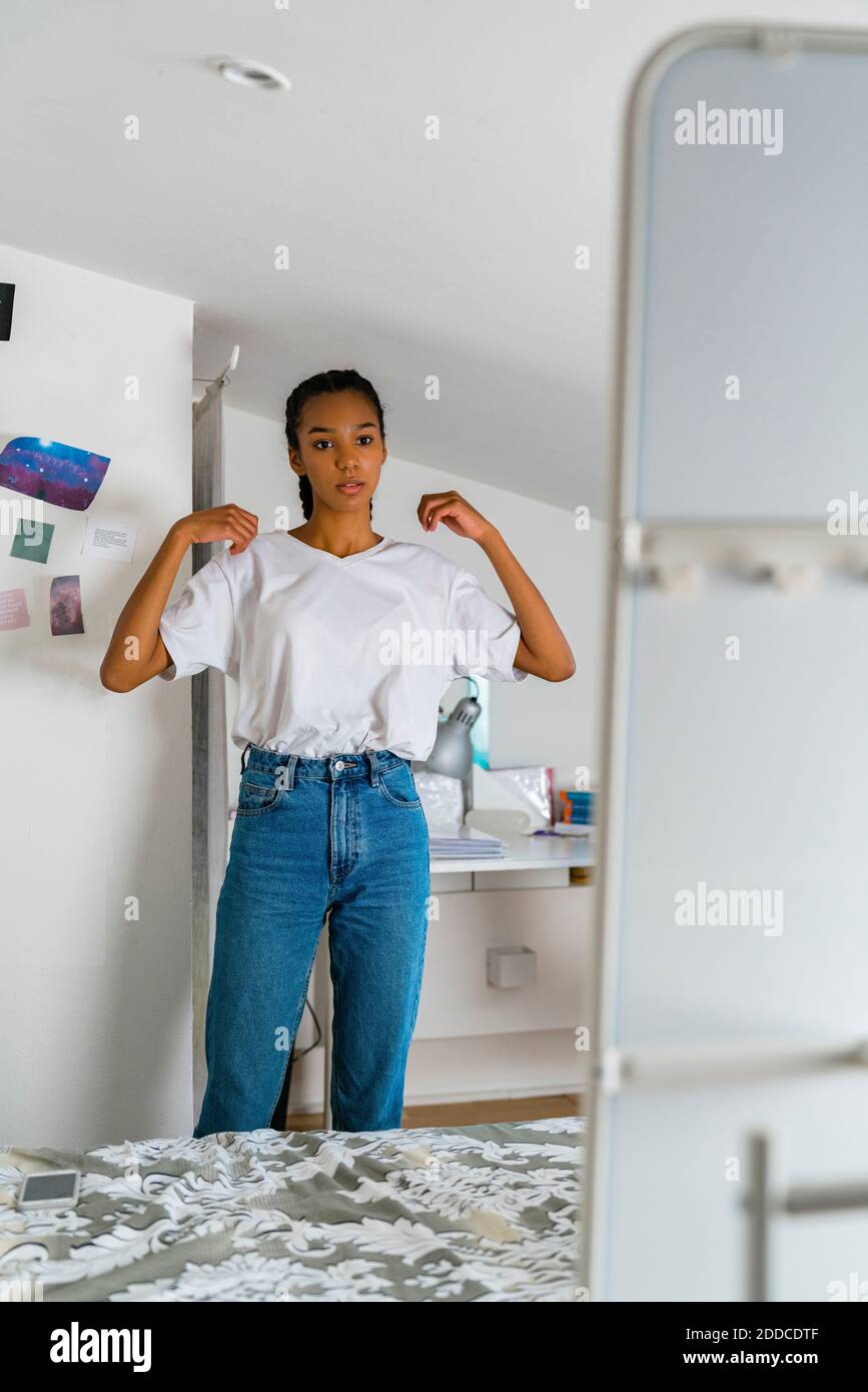 Teenage girl looking in mirror while standing at home Stock Photo