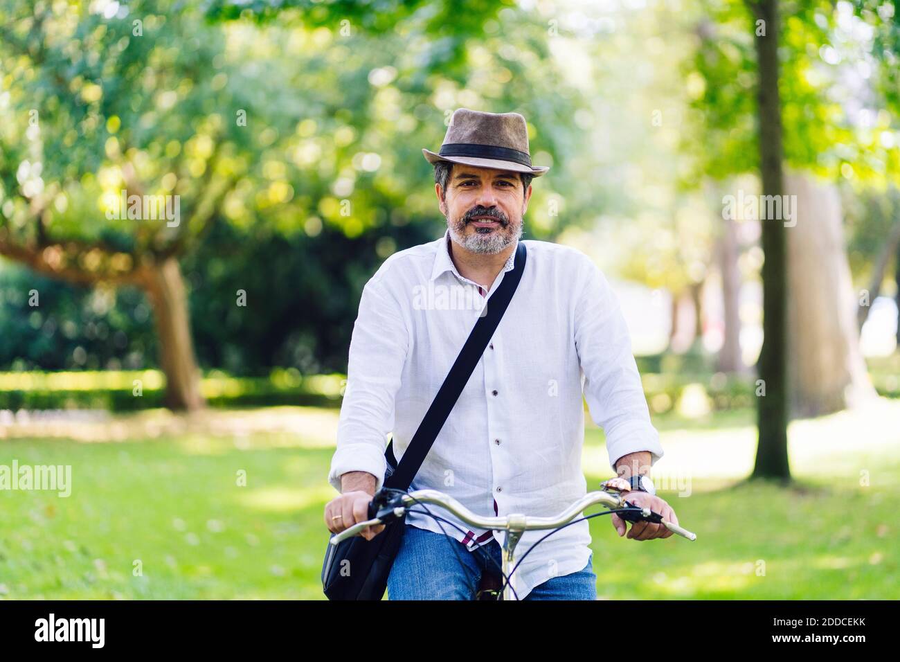 Mature man smiling while cycling in park Stock Photo