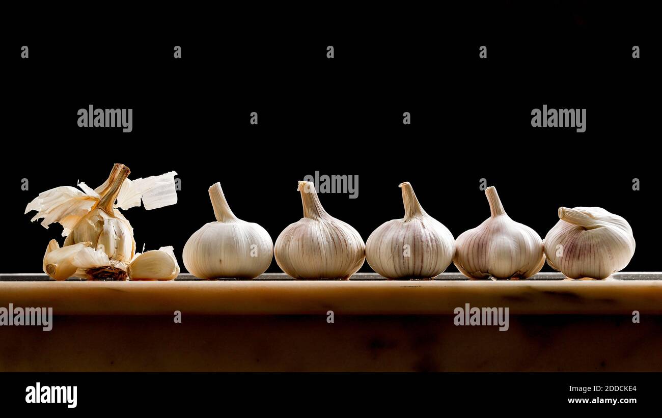Garlic bulbs shot on a marble table top in a fun way as if the garlic bulb on the left is preaching to his flock Stock Photo