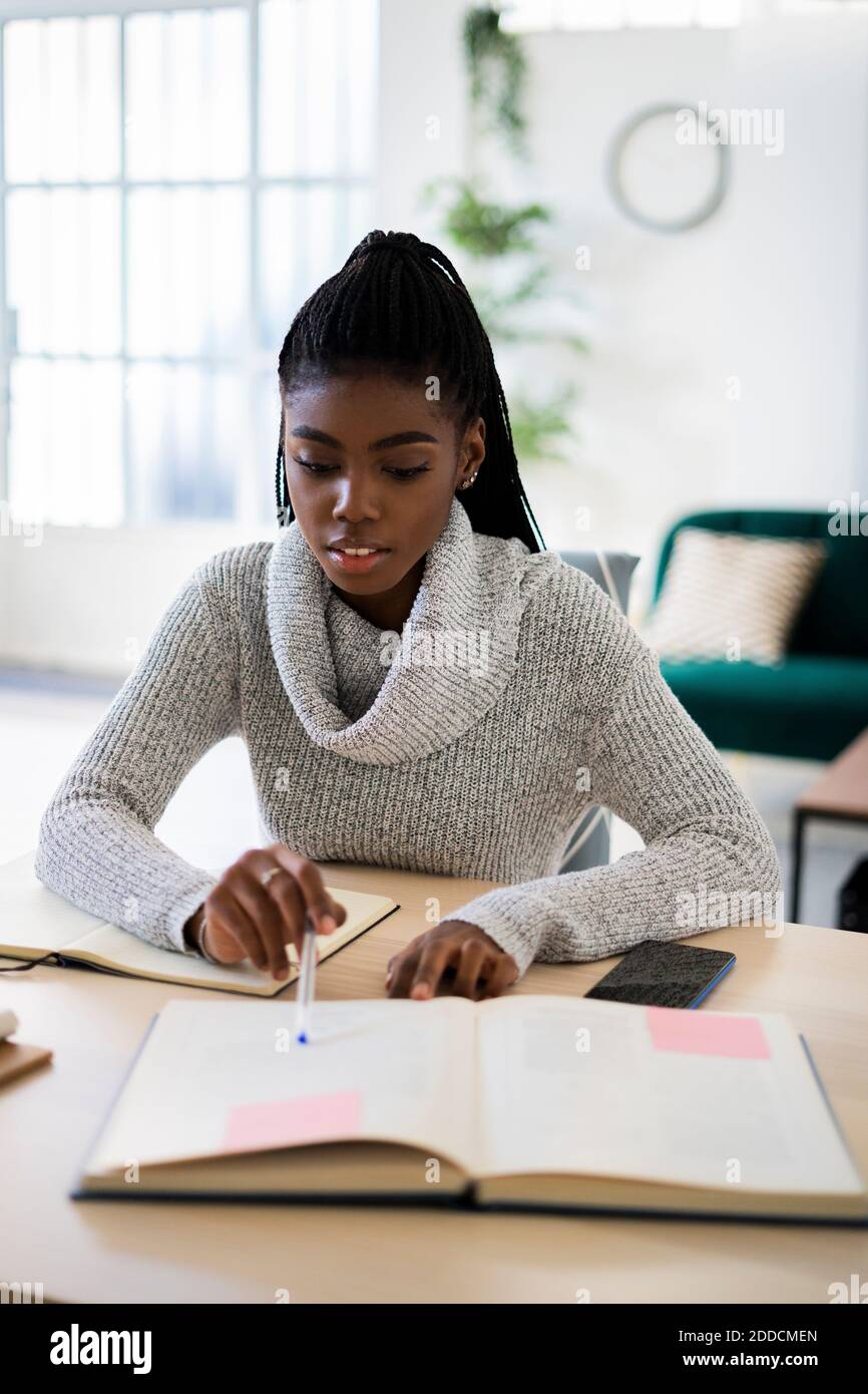 Young woman doing homework while sitting at home Stock Photo