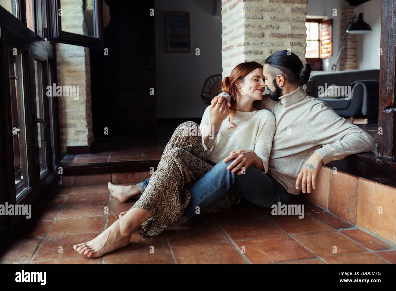 Couple rubbing nose while sitting on floor at home Stock Photo
