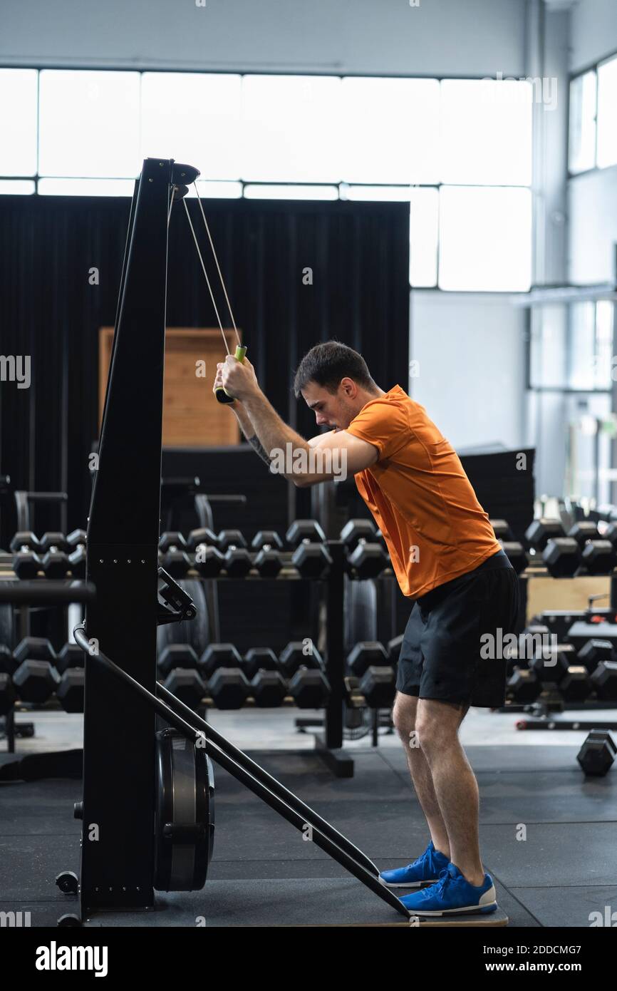 Male athlete pulling resistance band while doing exercise in gym Stock