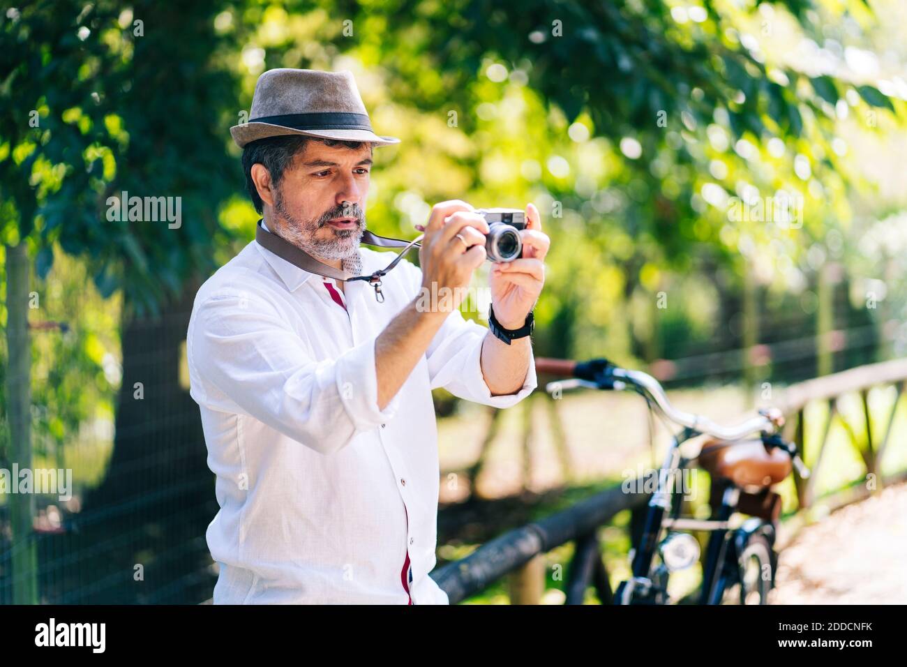 Mature man clicking picture with camera while standing in park Stock Photo
