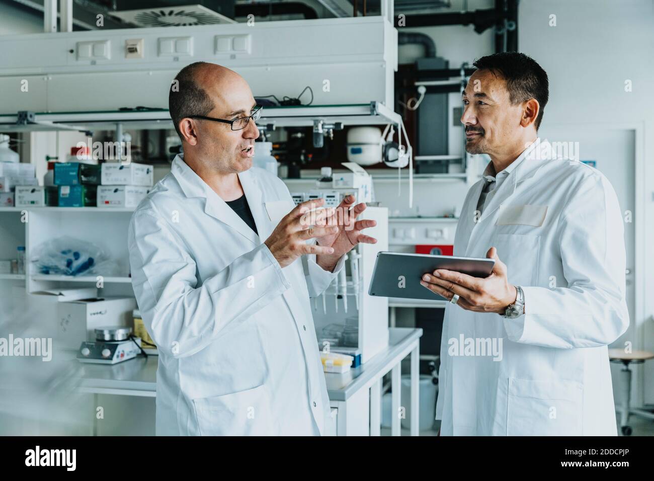 Scientists discussing while using digital tablet at laboratory Stock Photo
