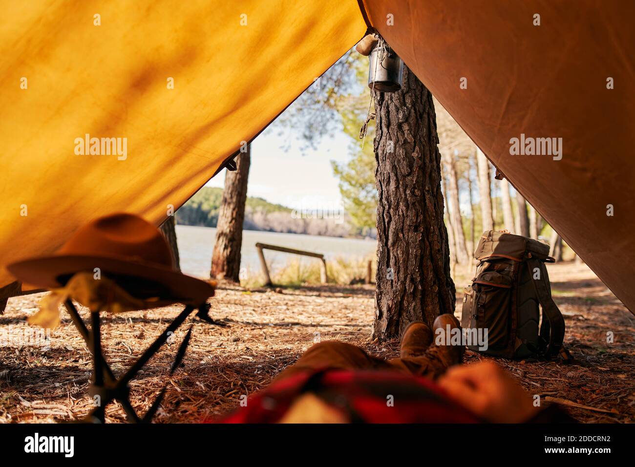 Low section of bushcrafter lying down under camping tent Stock Photo