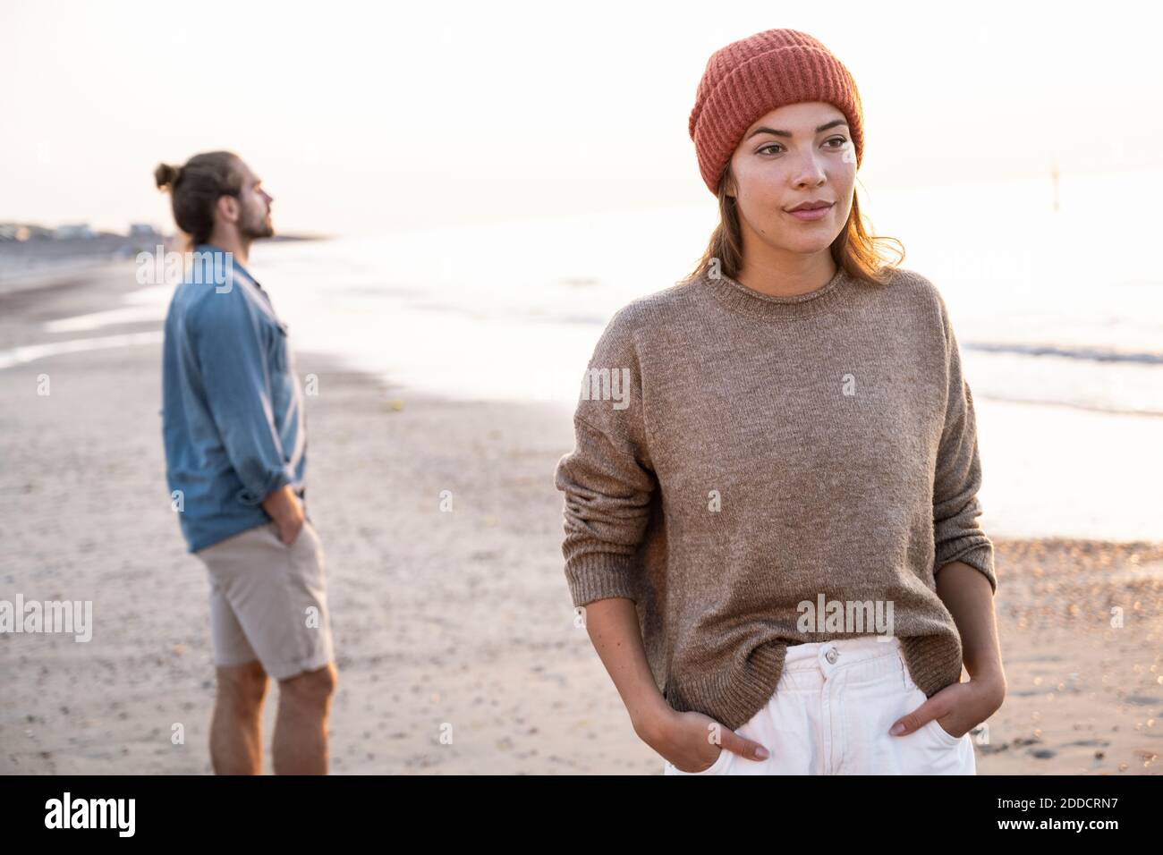 Beautiful young woman standing with hands in pockets against boyfriend ...