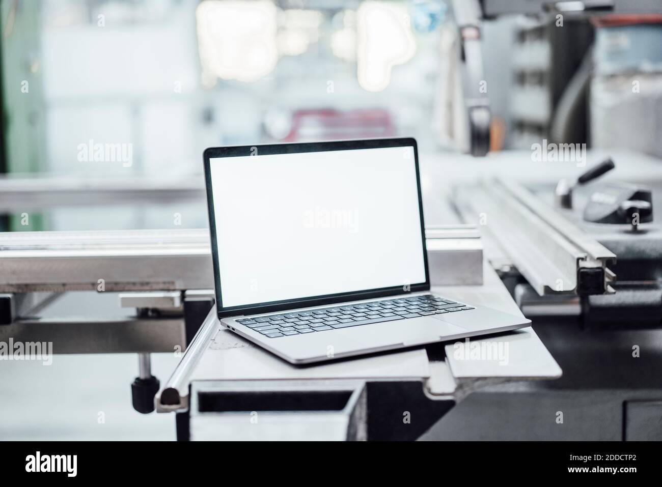 Laptop with blank screen on machinery in factory Stock Photo