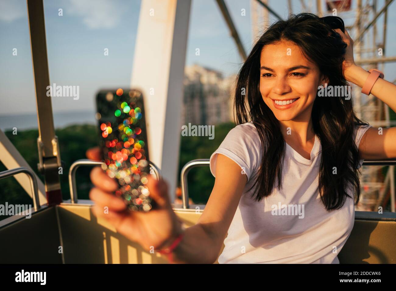 Happy beautiful woman taking selfie on Ferris wheel at amusement park Stock Photo